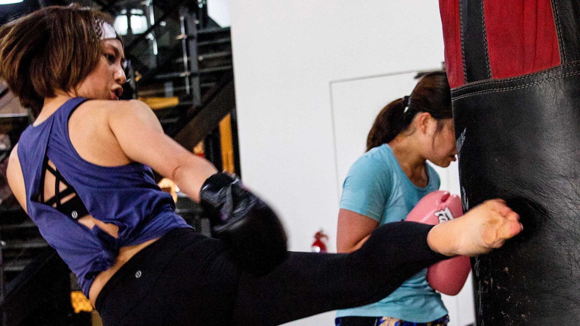 A women kicking a heavy bag during a Muay Thai class