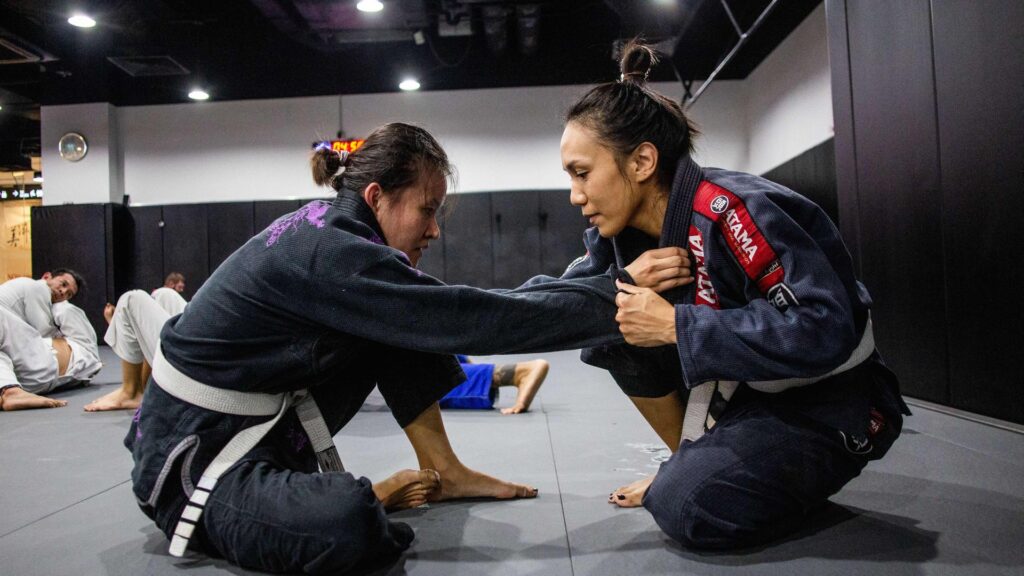 Two people sparring in BJJ class.