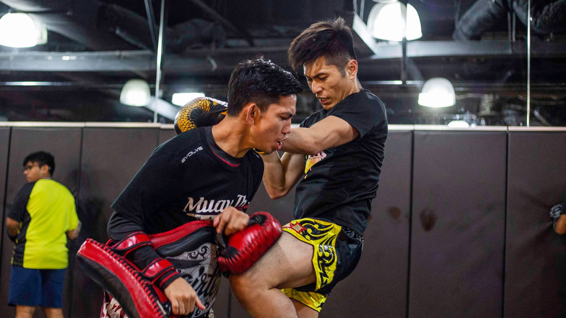 Someone throwing a knee in Muay Thai training.