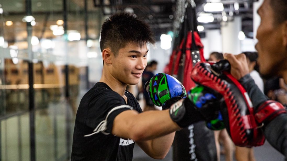 A student smiling while throwing a punch in Muay Thai class.