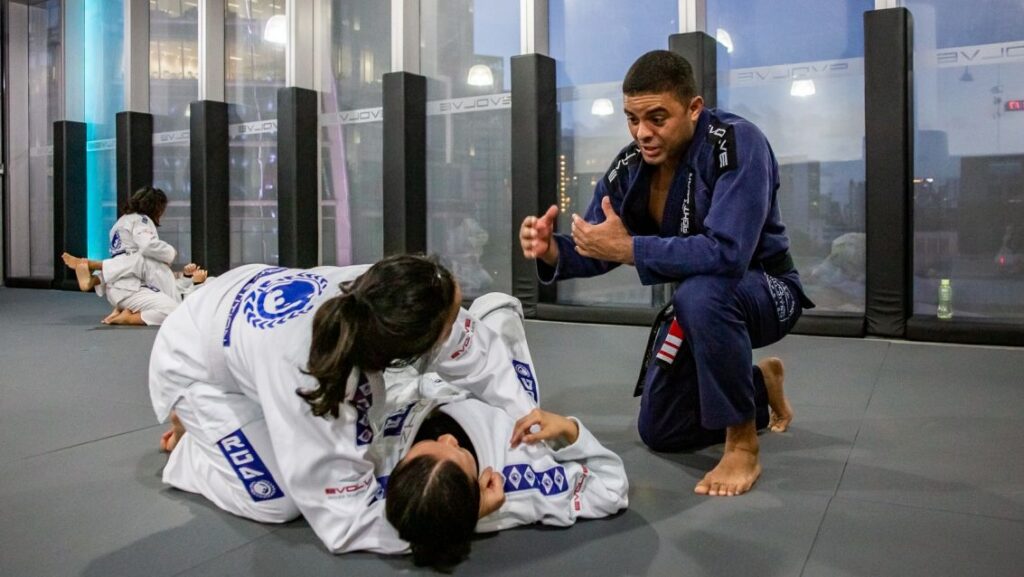 A BJJ professor teaching two students in class.