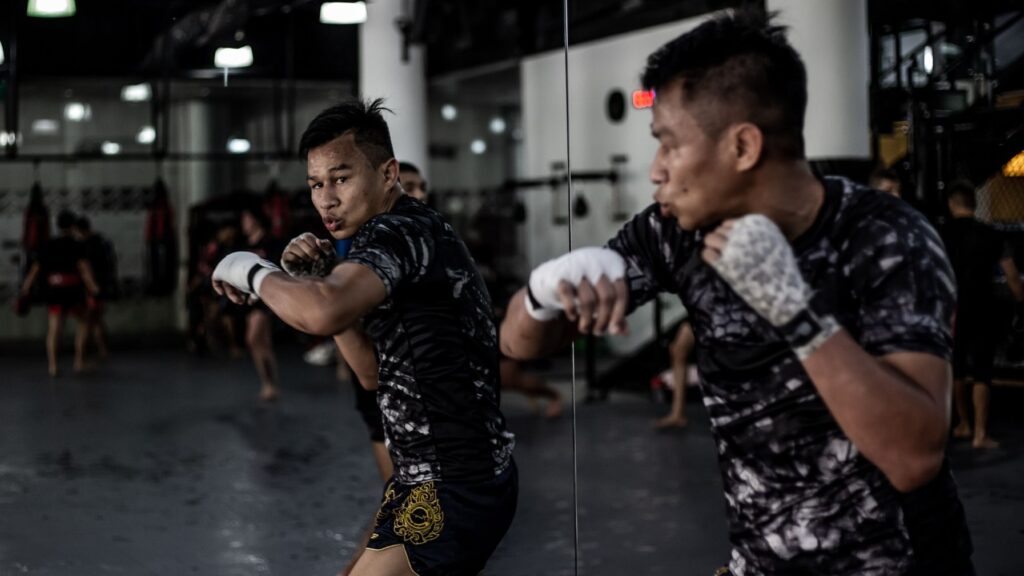 A boxer throws a hook punch in front of a mirror