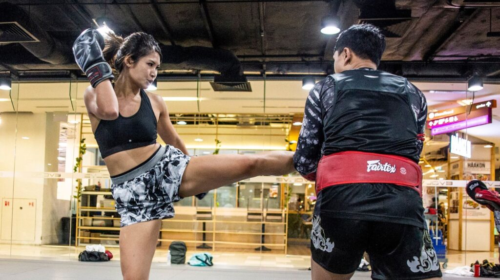 A female Muay Thai student throws a kick during a class