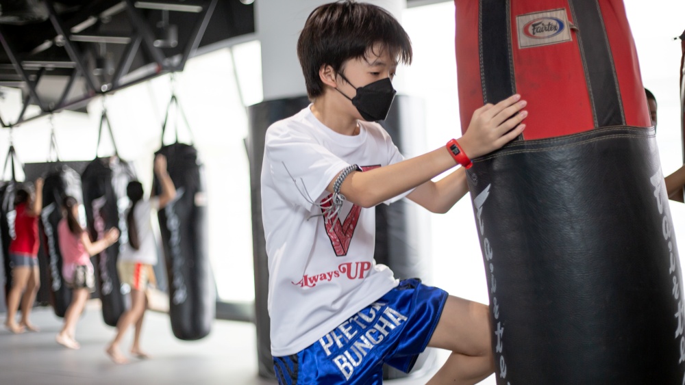 boy doing weight training exercises in muay thai class for kids